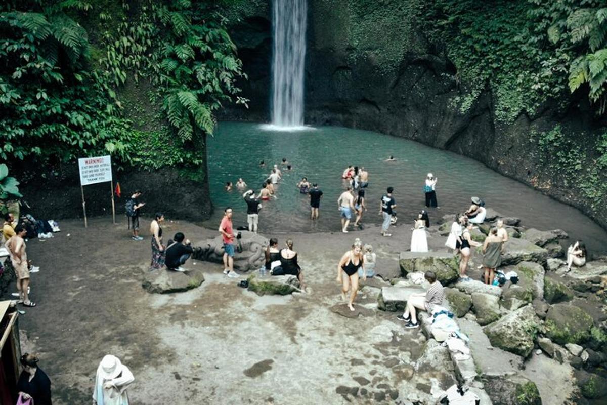 sekumpulan orang di dalam air berhampiran air terjun
