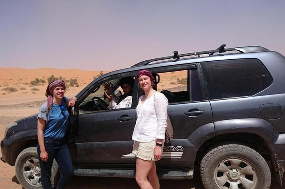 duas mulheres em pé na frente de um carro no deserto