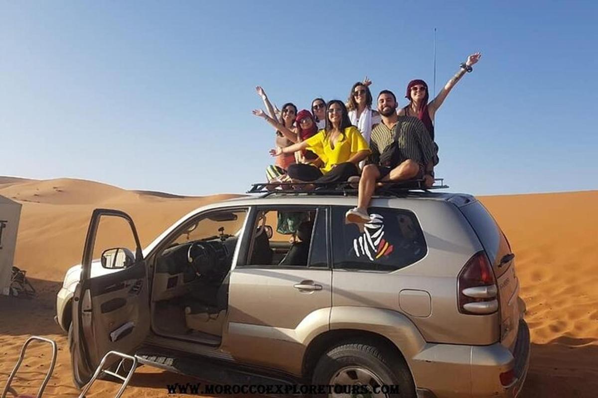 um grupo de pessoas sentadas no teto de um carro no deserto