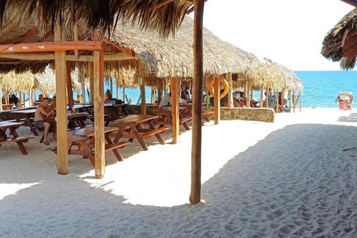a beach with tables and straw umbrellas and the ocean