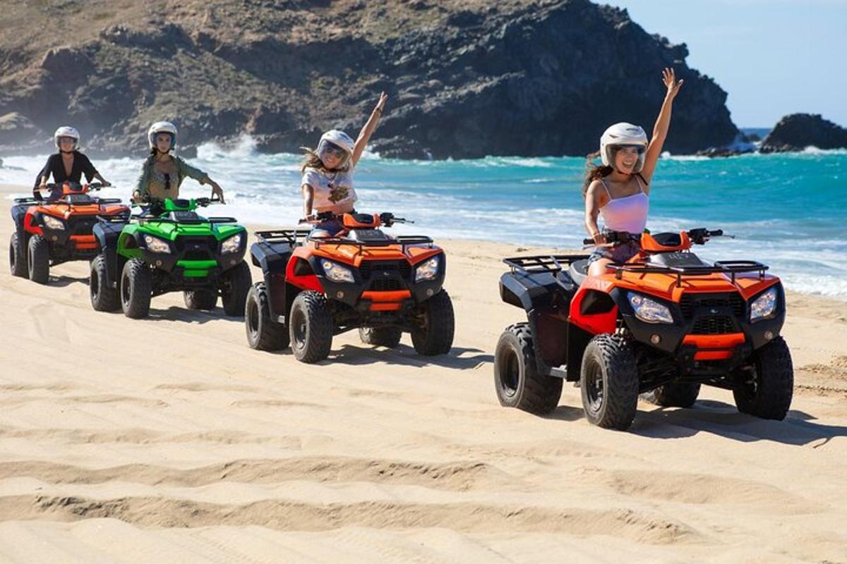 un grup de persones conduint quads a la platja