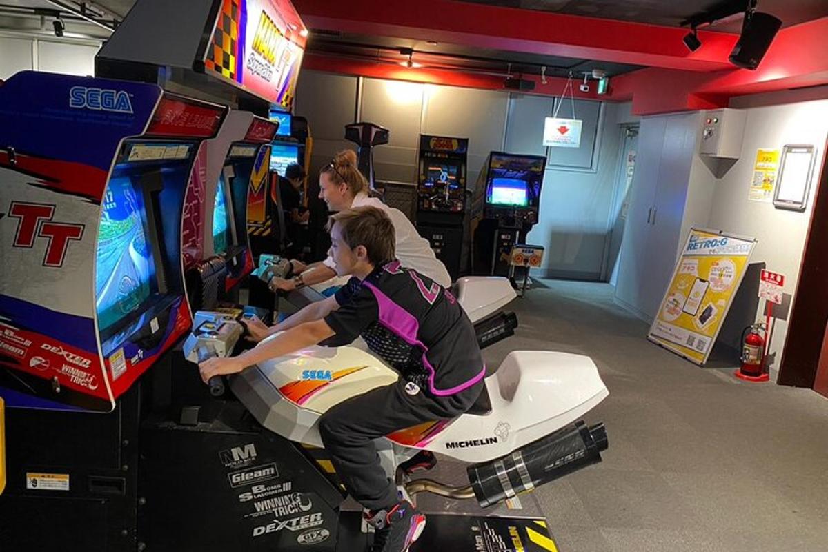 Dos personas jugando videojuegos en una sala de videojuegos.