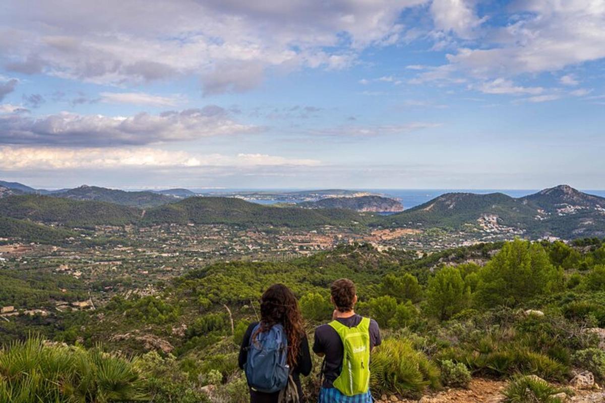 two people standing on top of a hill overlooking a city