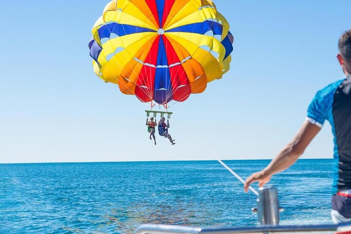 muž letící s barevným padákem nad oceánem
