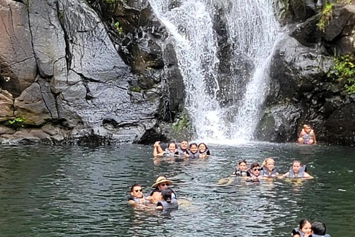 група људи плива у води близу водопада