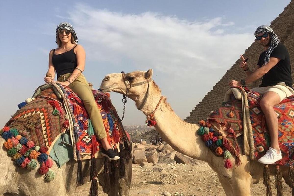 muž a žena jedoucí na velbloudovi poblíž pyramid