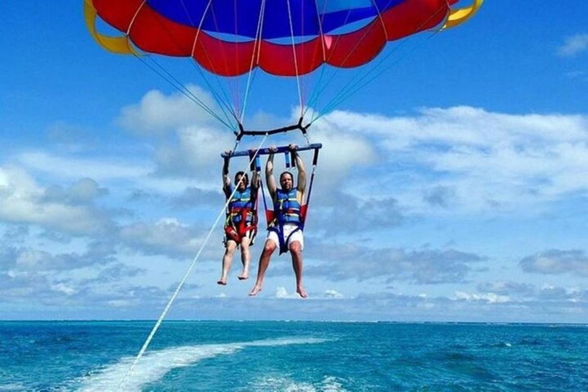 drie mensen zitten aan een parachute boven de oceaan