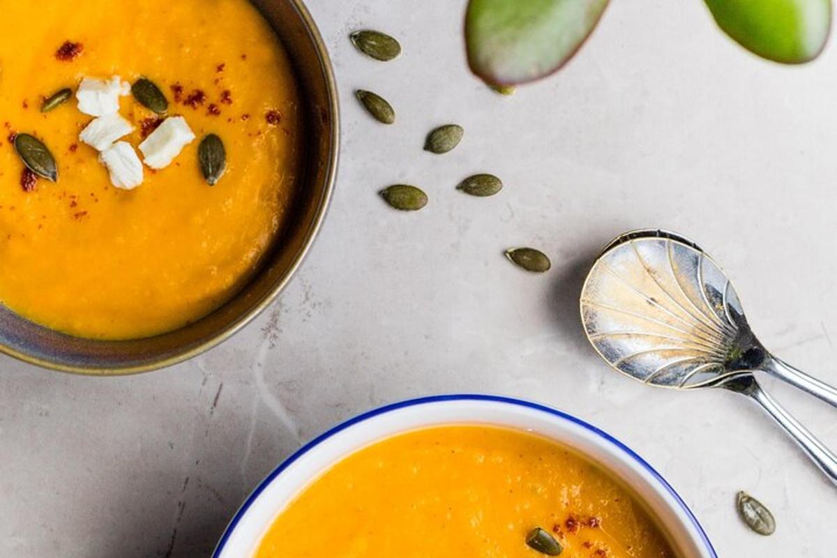 a bowl of soup next to a pot of pumpkin soup