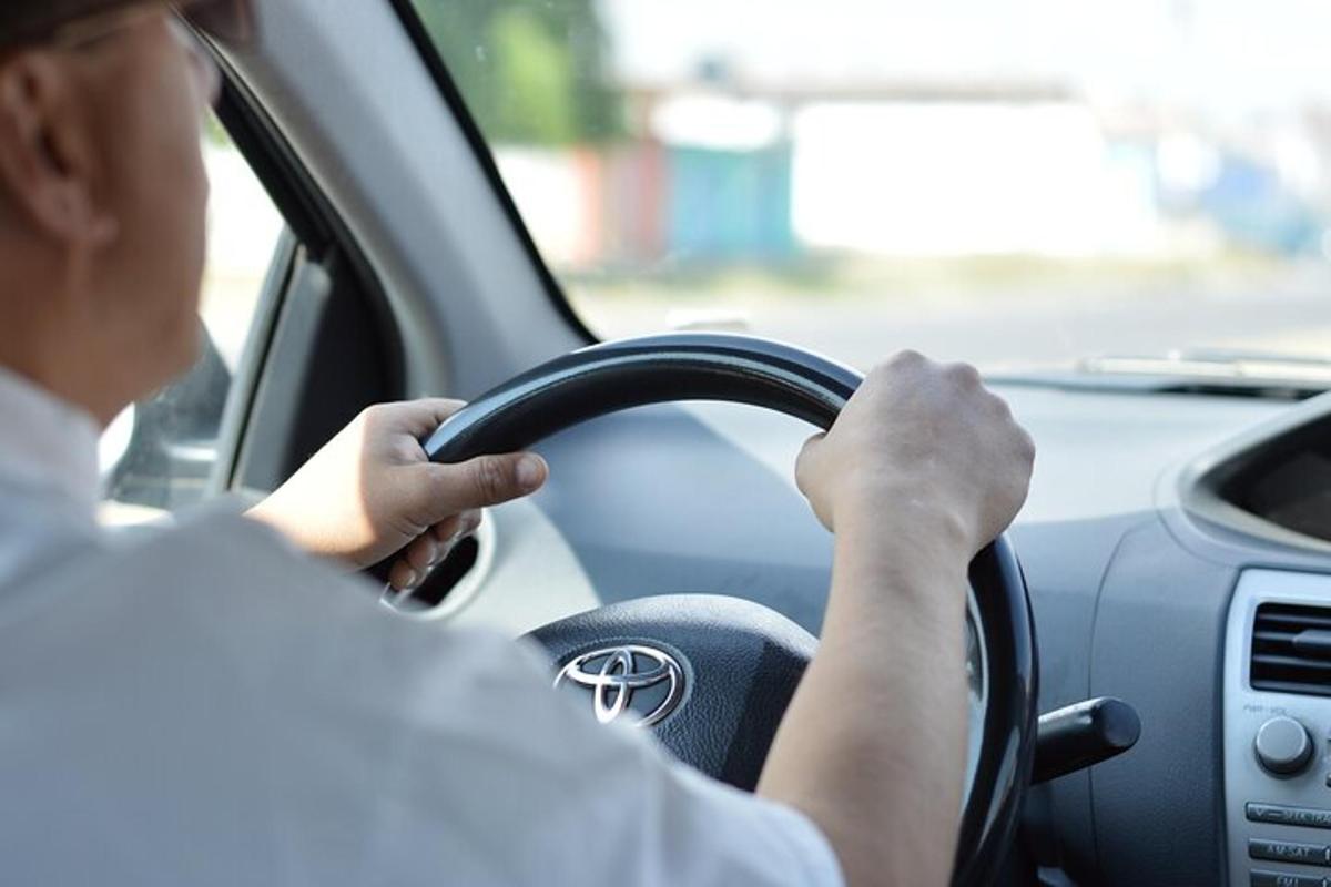 vyras, vairuojantis automobilį, rankomis laikydamas vairą