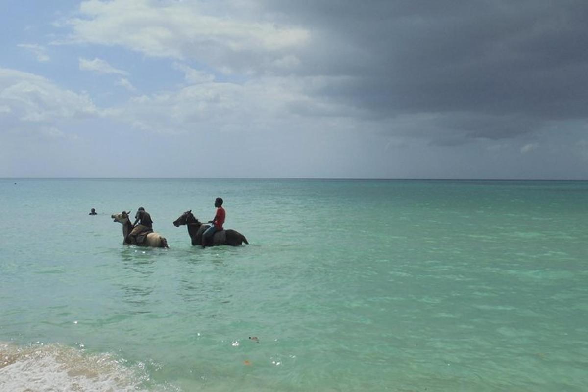 Dos personas montando a caballo en el agua en la playa.