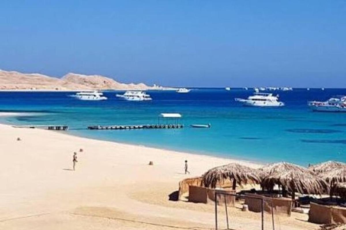 Una playa con algunas personas y barcos en el agua.