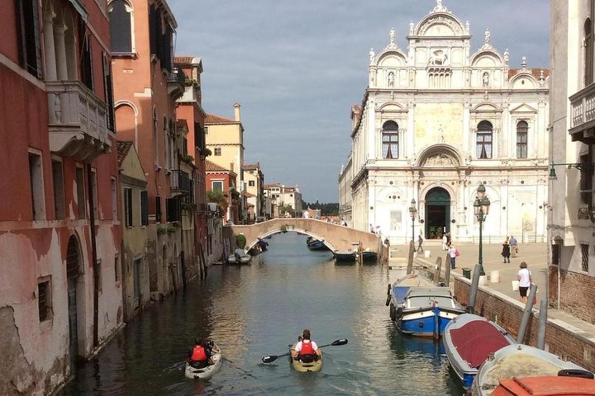 un grup de persones en canoes per un canal d'una ciutat