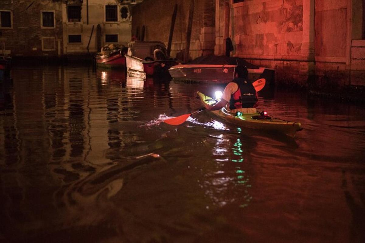 Un hombre en un kayak en el agua por la noche.