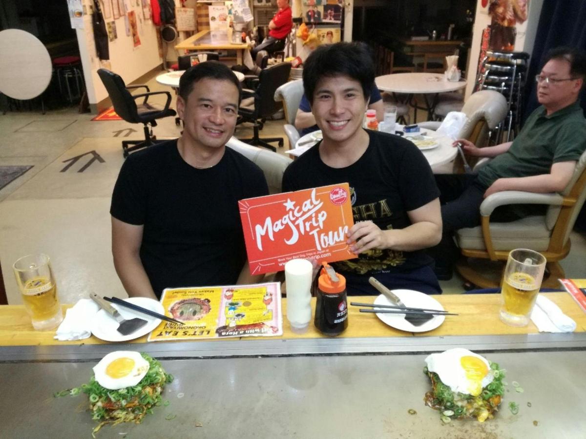 two men are sitting at a table with food