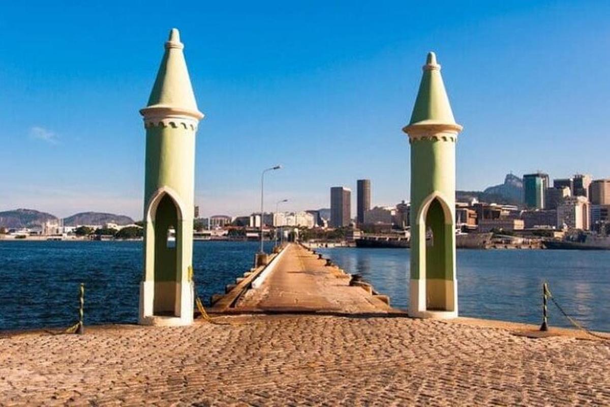 um píer com três torres na água com uma cidade