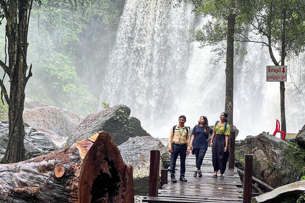 sekelompok orang berjalan di jembatan di depan air terjun