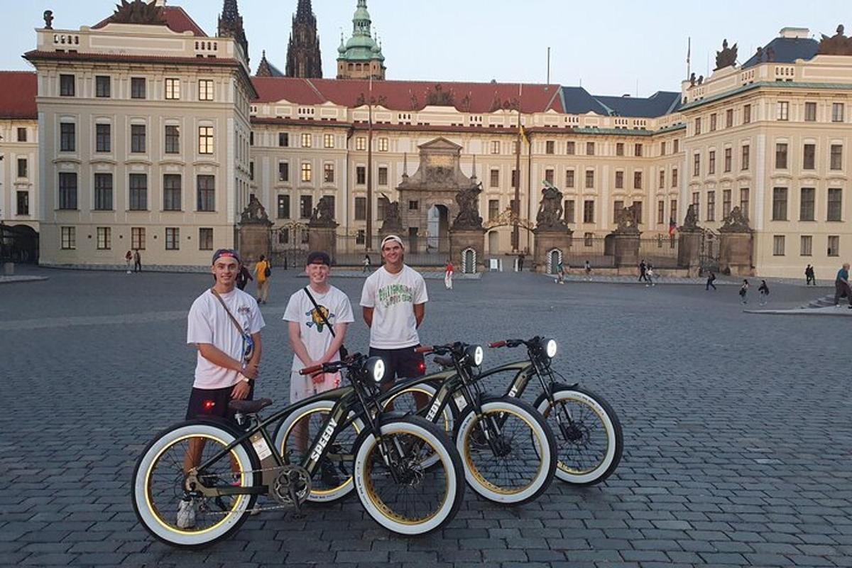 tři lidé stojící před budovou s koly