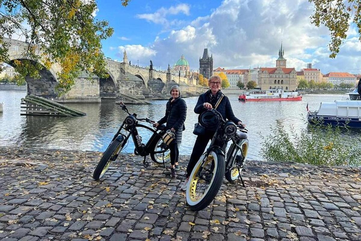 dva lidé sedící na motorkách vedle řeky