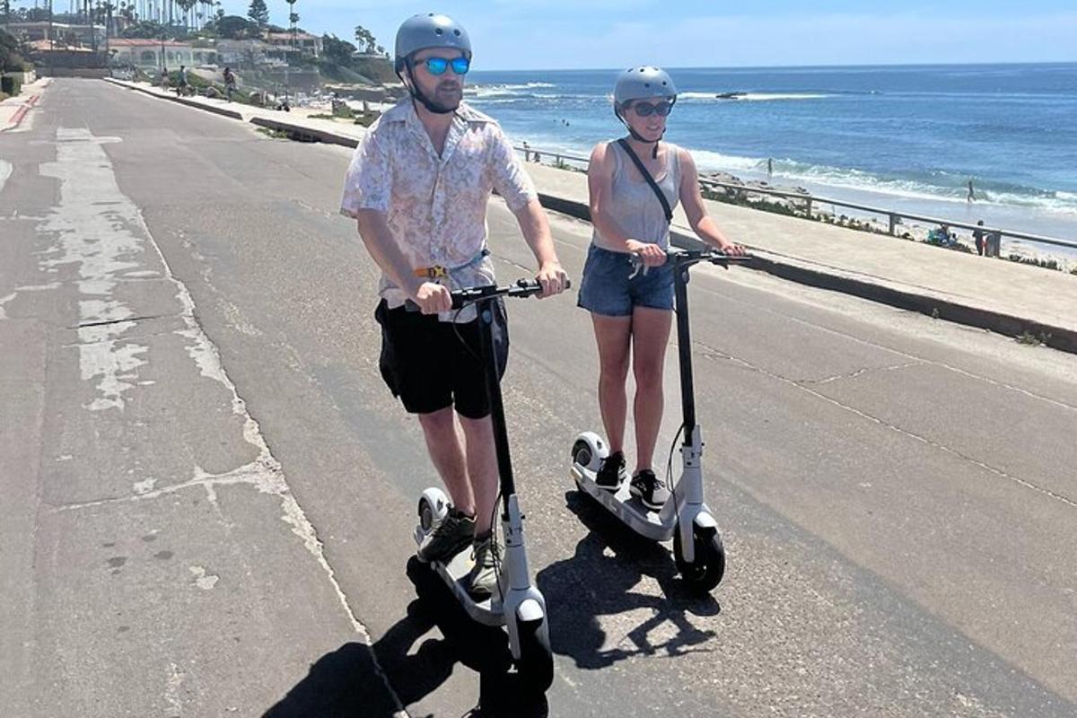 egy férfi és egy nő robogóznak a tengerparton
