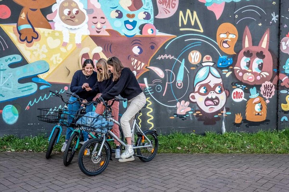 kaks naist sõidavad jalgratastega grafitiga kaetud seina ees