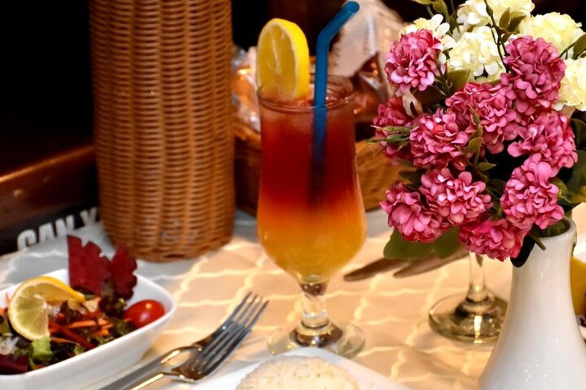 Una mesa con una bebida y un jarrón de flores.