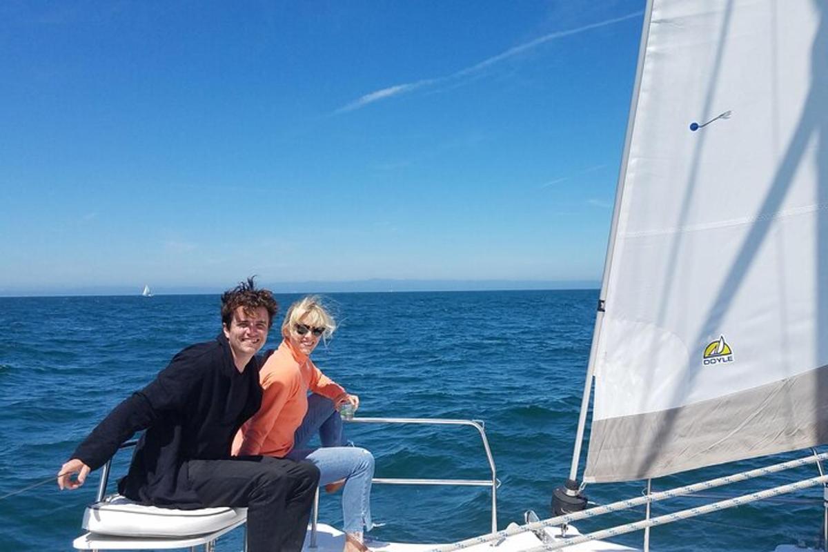 a man and woman sitting on the back of a sailboat