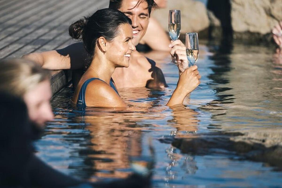 un uomo e una donna che tengono in mano dei bicchieri di vino in una piscina