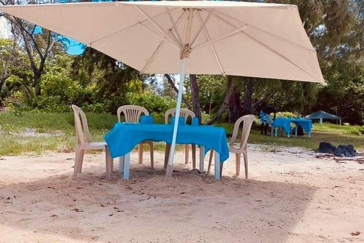 stół i krzesła pod parasolem na plaży