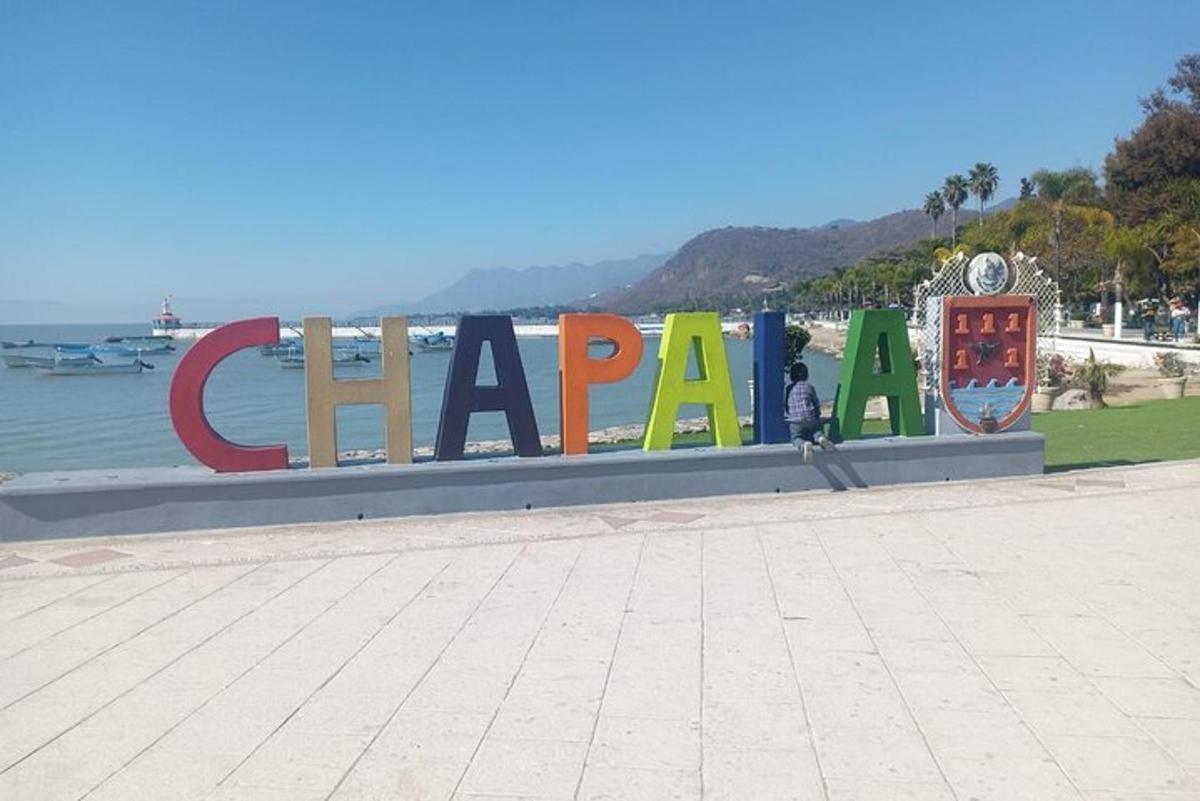 a sign for a beach with a man standing in front of it