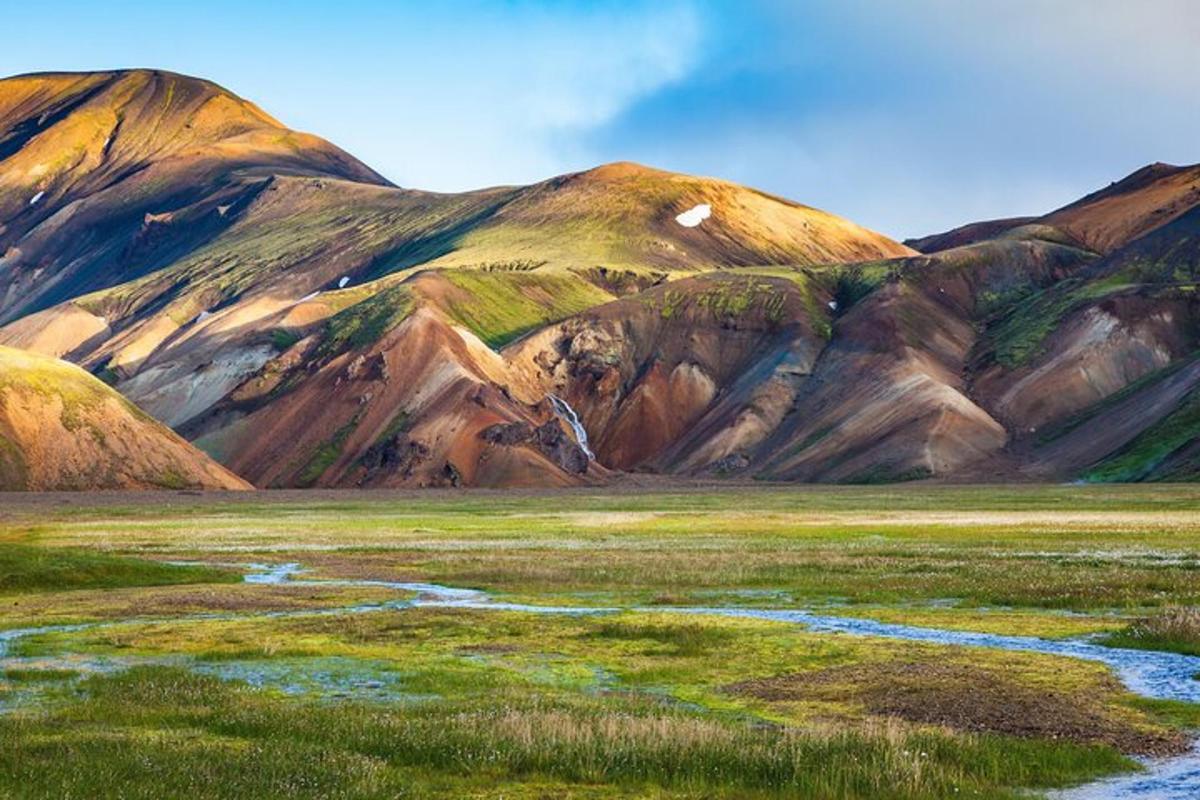 a mountain range with a river in a field