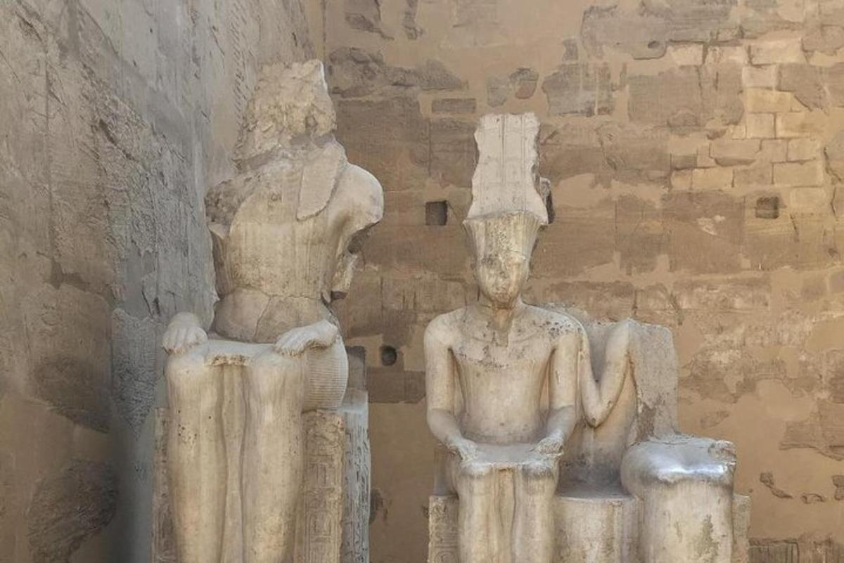 ένα άγαλμα δύο ανθρώπων που στέκονται δίπλα σε έναν τοίχο