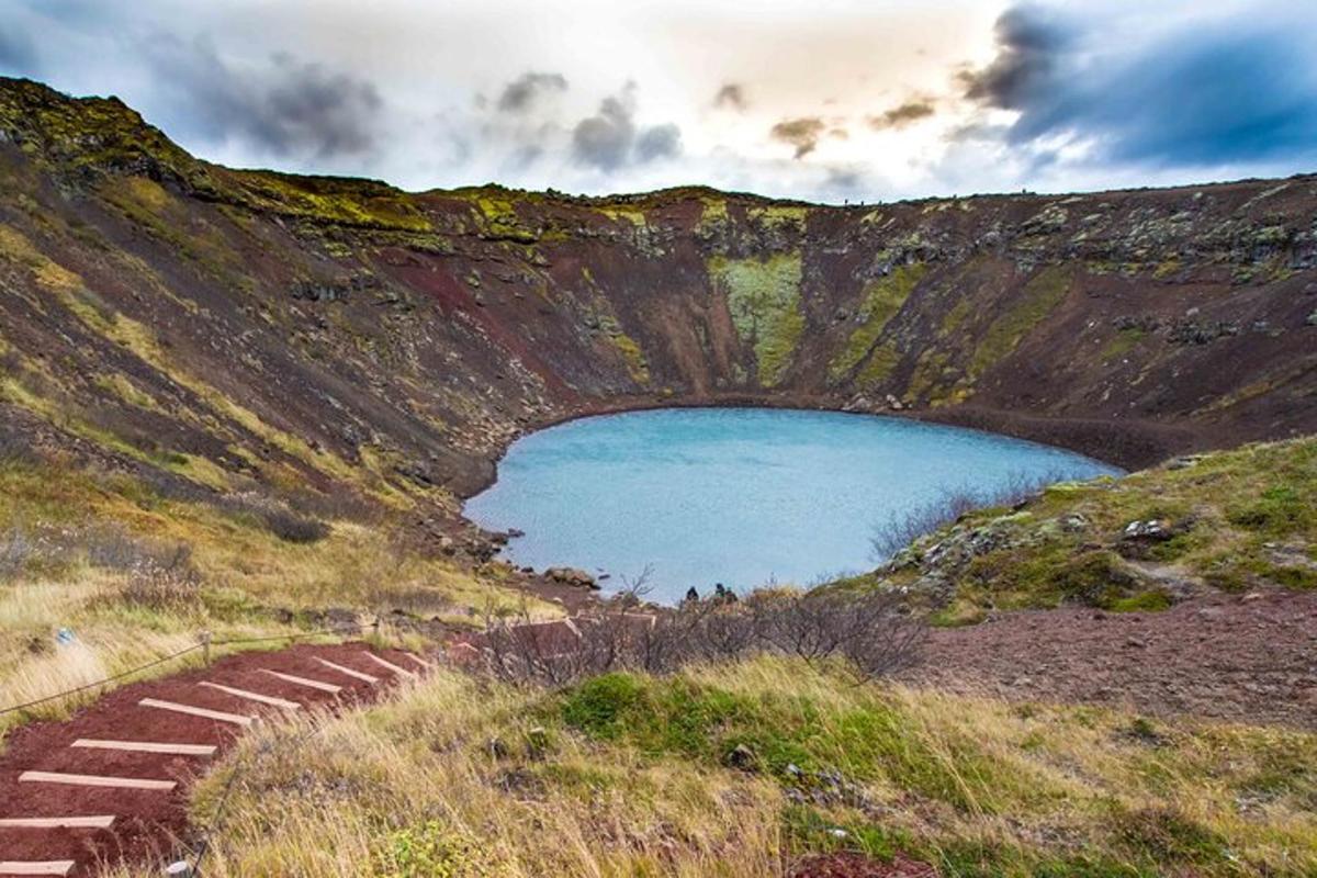 una montaña con un lago azul en medio de una colina