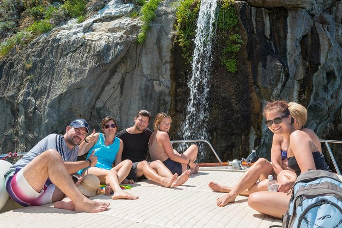 un grup de persones assegudes en una barca davant d'una cascada