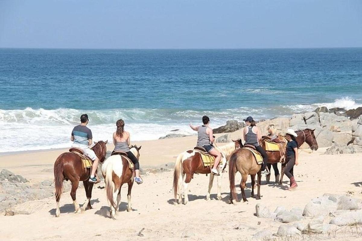 a group of people riding horses on the beach