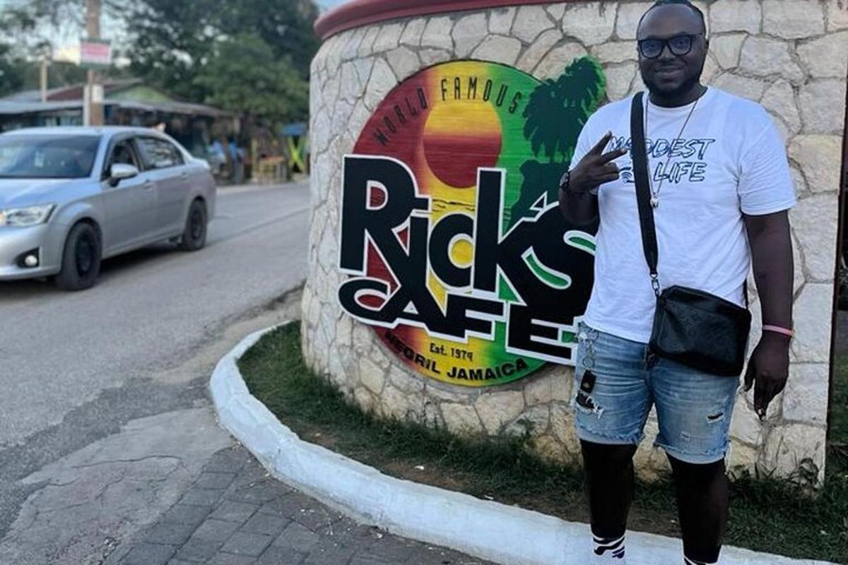um homem parado em frente a uma placa de um café de pedras