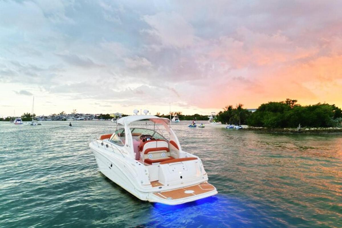 a white boat on the water with a sunset