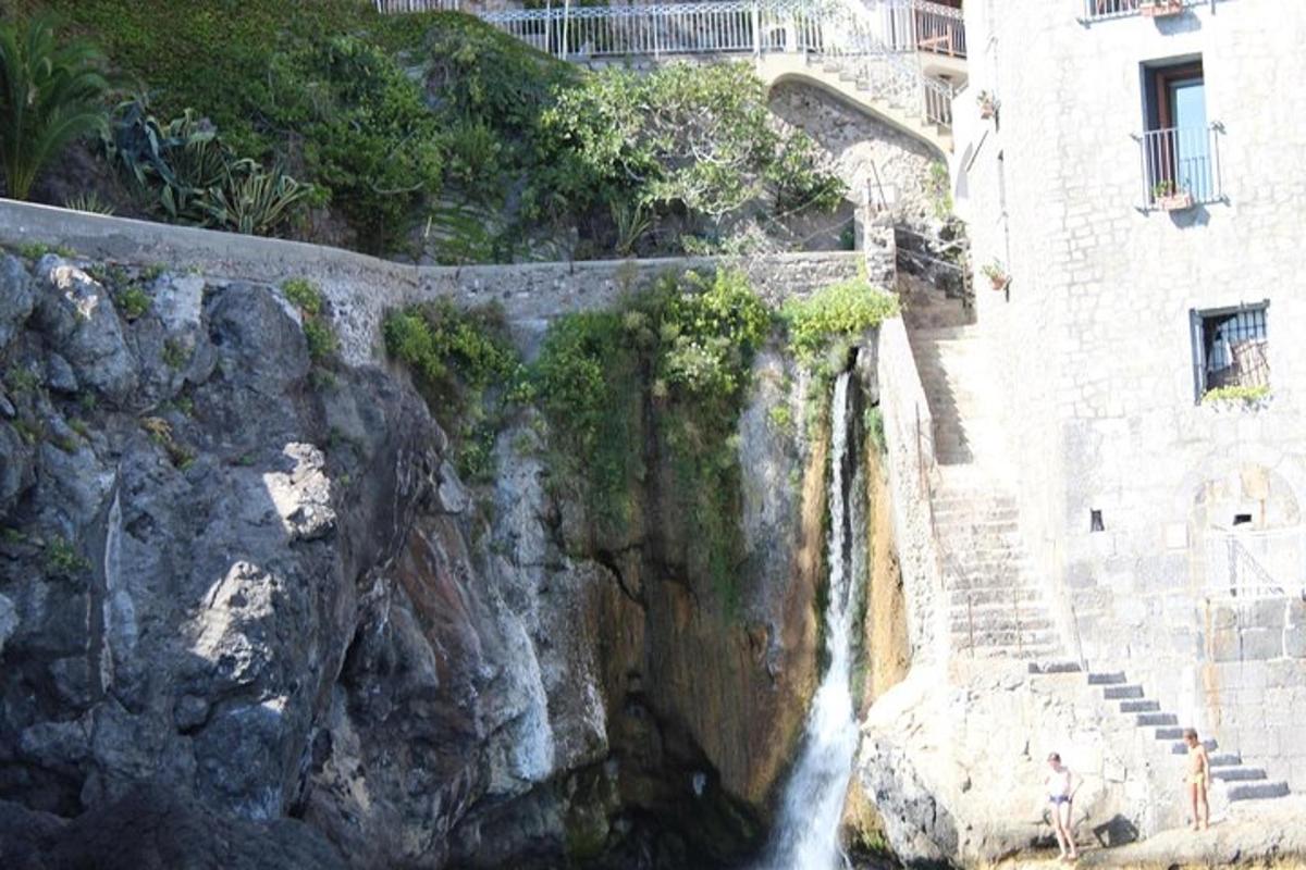 ένας πέτρινος τοίχος με έναν καταρράκτη δίπλα σε ένα κτίριο