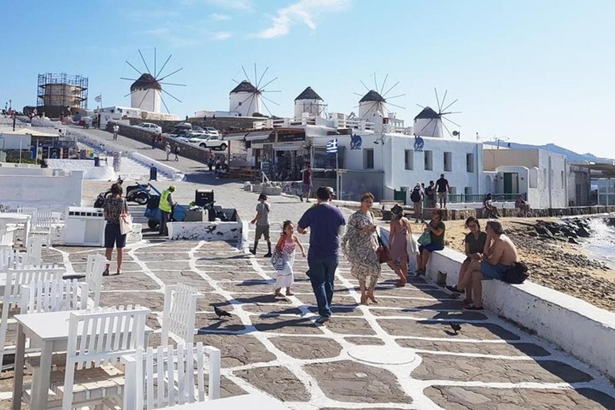 Μια ομάδα ανθρώπων που περπατούν σε μια παραλία με ανεμόμυλους