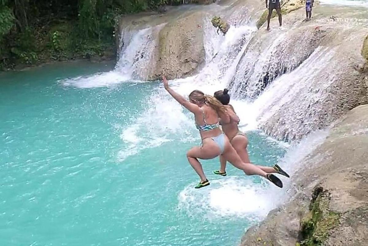due donne in costume da bagno che saltano in una cascata