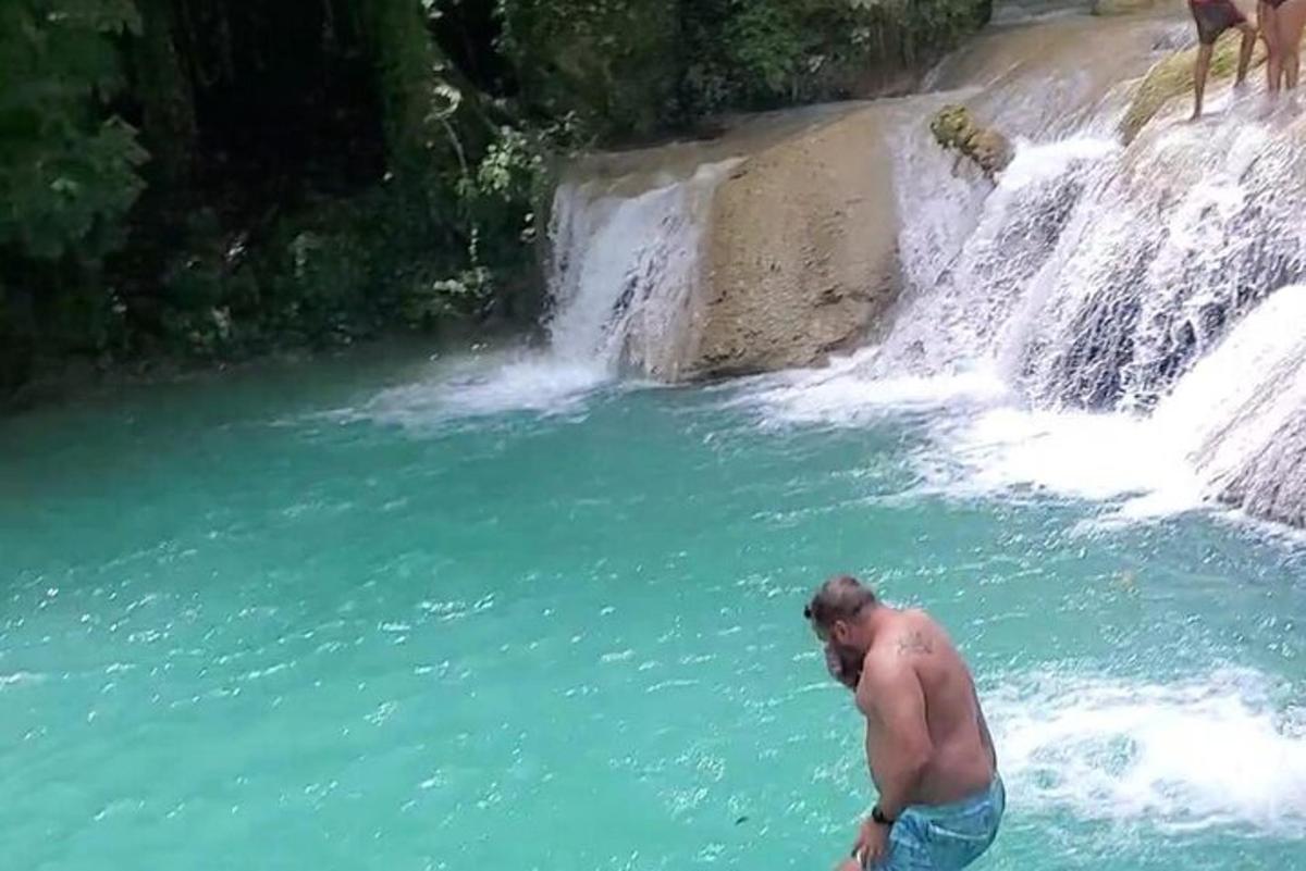 un uomo in piedi nell'acqua accanto a una cascata