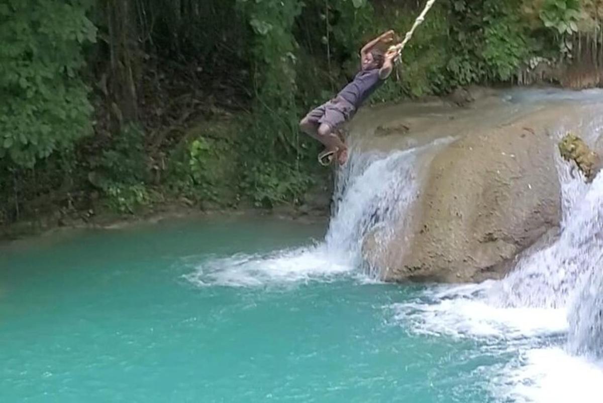 een man springt van een rots in een rivier