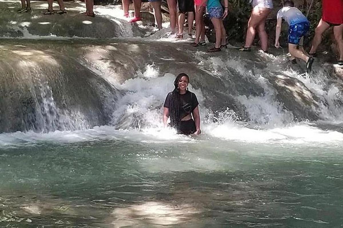 чоловік стоїть у воді перед водоспадом