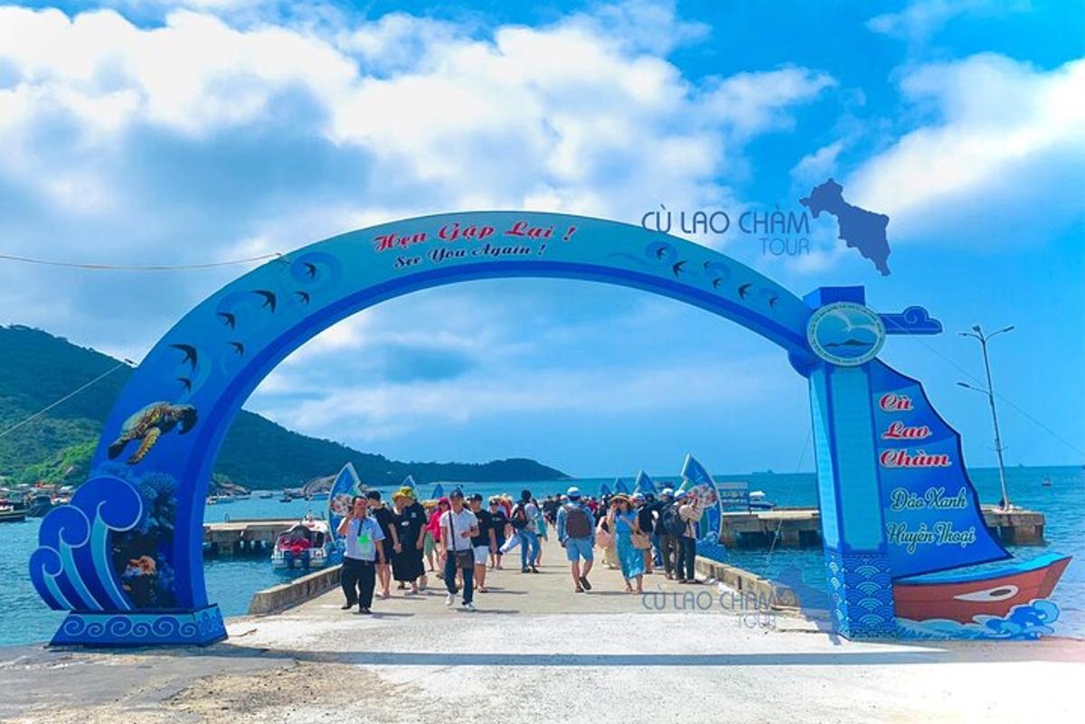 un gruppo di persone che cammina sotto un arco blu sopra l'acqua