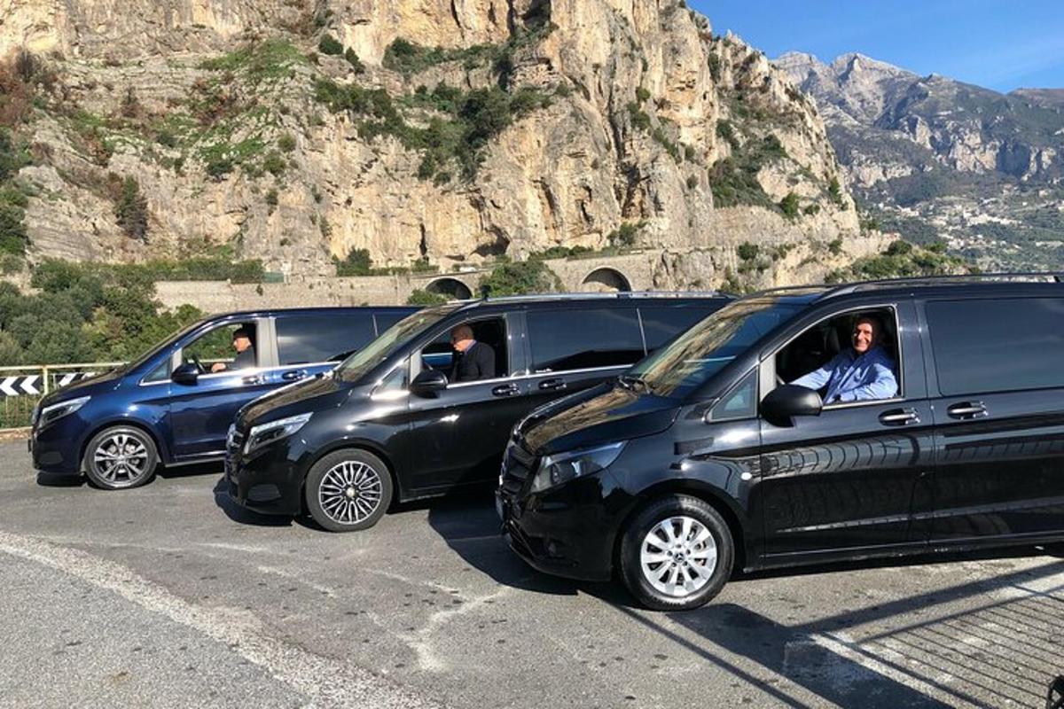 three cars parked in a parking lot next to a mountain