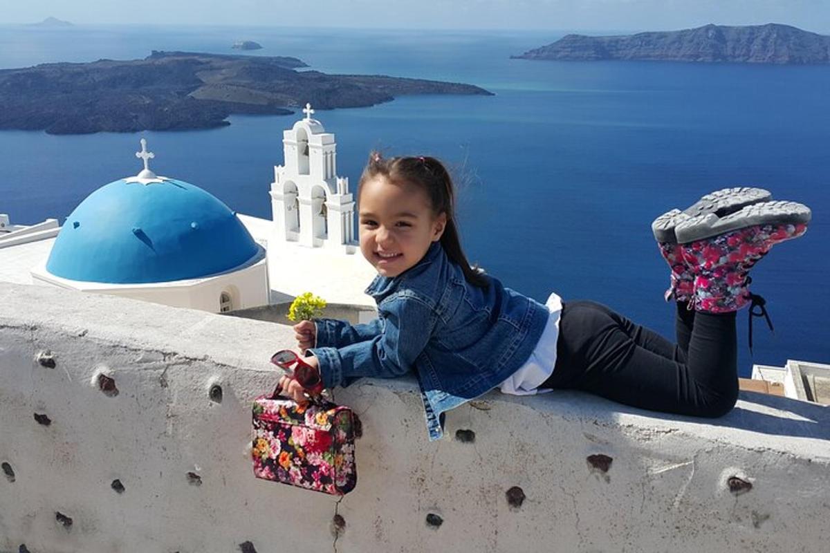 una bambina seduta su un muro che tiene in mano una pianta