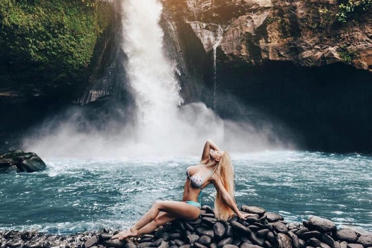 una dona asseguda en una roca davant d'una cascada