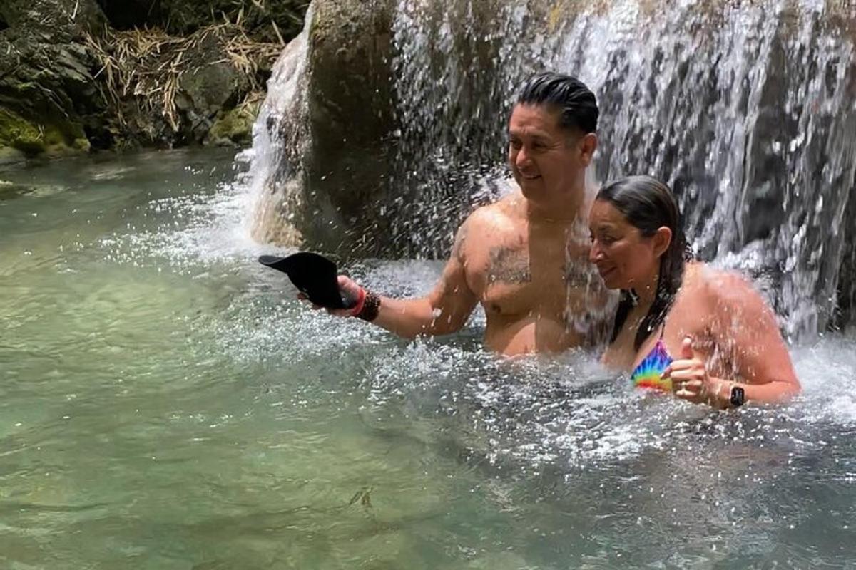 một người đàn ông và một người phụ nữ ở dưới nước gần thác nước