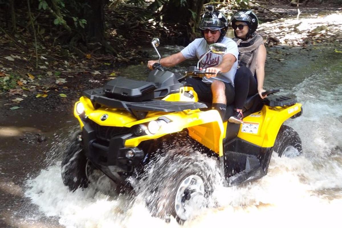 two people riding on a four wheeler through a river