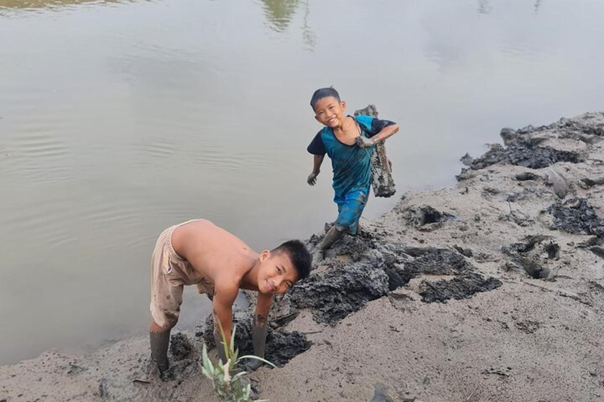 two young boys playing on the shore of a body of water
