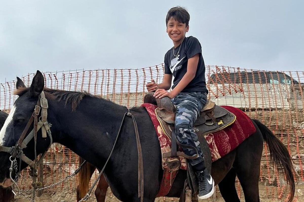 a young boy riding on the back of a horse
